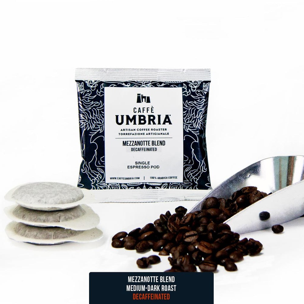 three espresso pods, coffee beans and coffee scoop with a blue pod pouch mezzanotte decaf