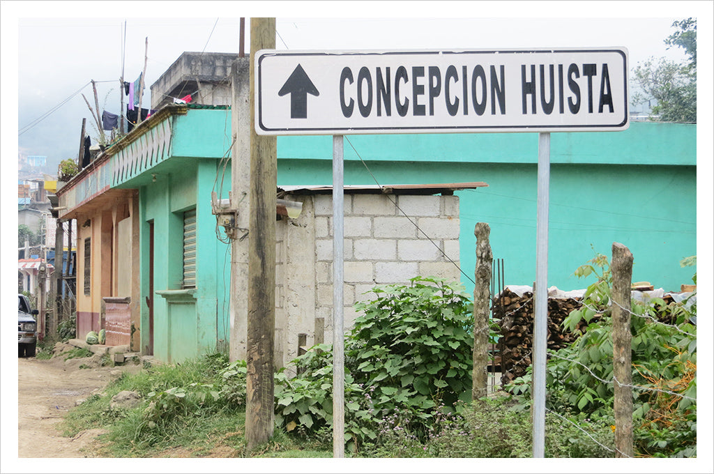 a road sign for Concepcion Huista in front of a turquoise building in Guatemala