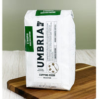 Umbria Coffee Roasters Ethiopia coffee bag on a wooden cutting board with a green background. Light roast