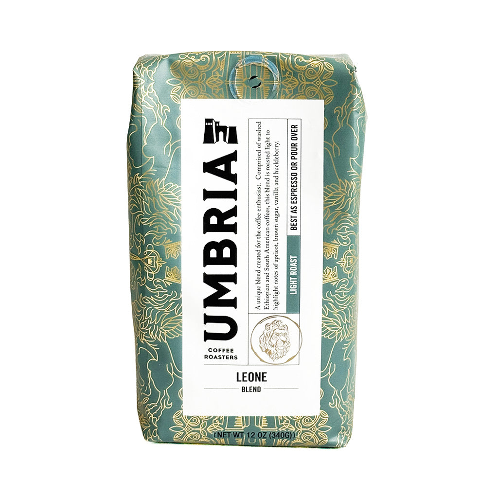 A 12 oz bag of Umbria Coffee Roasters Leone Blend light roast coffee, featuring a green and gold patterned bag with a white label.