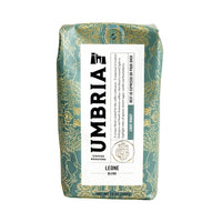 A 12 oz bag of Umbria Coffee Roasters Leone Blend light roast coffee, featuring a green and gold patterned bag with a white label.
