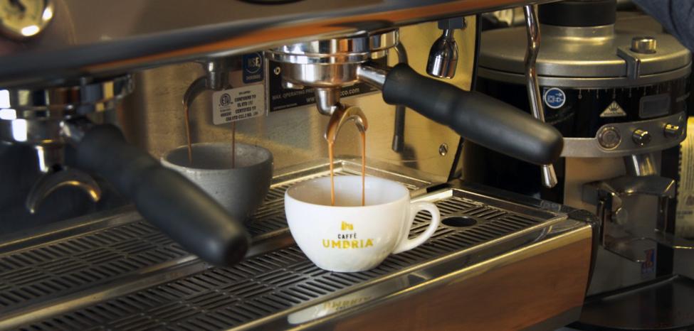 coffee dripping into cup from portafilter in espresso machine