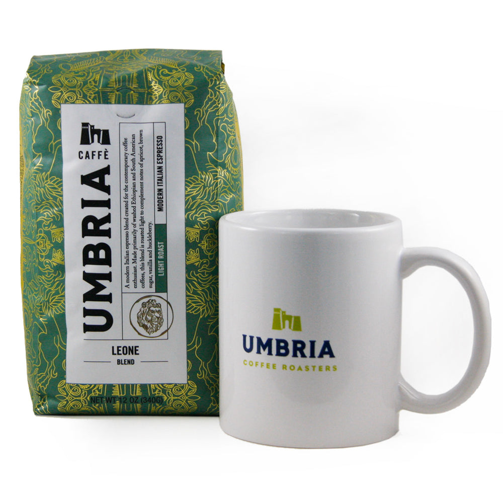 A green bag of coffee with gold design and a white porcelain mug with yellow and blue logo